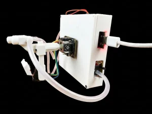 Colibrí V1.0 de lado sobre fondo negro: el joystick en la cara frontal con la boquilla en su palanca, el botón del labio debajo y el cable USB-C trenzado conectado al lateral.